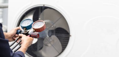 Teknisyen klimayı kontrol ediyor, klimaları doldurmak için ekipmanları ölçüyor..