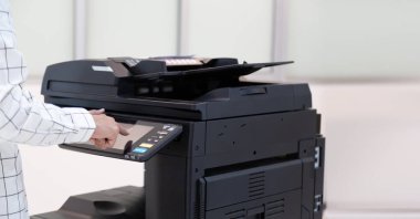 İşadamı, yazıcı fotokopi ağı panelindeki düğmeye basar, ofis konseptinde fotokopi üzerinde çalışır, yazıcı, kağıt tarama ve kopyalama için ofis çalışanı ekipmanıdır.