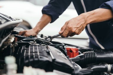 Otomobil tamircisi elleri ingiliz anahtarı, araba servisi ve bakımı ile bir araba motoru otomotiv atölyesini tamir ediyor..