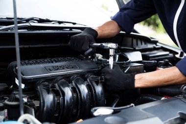 Otomobil tamircisi elleri ingiliz anahtarı, araba servisi ve bakımı ile bir araba motoru otomotiv atölyesini tamir ediyor.