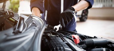 Otomobil tamircisi elleri ingiliz anahtarı, araba servisi ve bakımı ile bir araba motoru otomotiv atölyesini tamir ediyor.