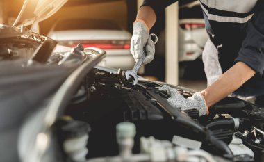Otomobil tamircisi elleri ingiliz anahtarı, araba servisi ve bakımı ile bir araba motoru otomotiv atölyesini tamir ediyor..