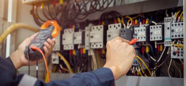 Elektrik mühendisi, devre kesici ve kablo tesisat sistemindeki elektrik akımını kontrol etmek için ölçüm ekipmanı kullanıyor. .