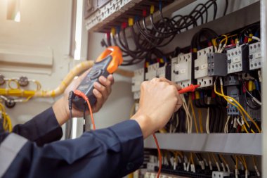 Elektrik mühendisi, devre kesici ve kablo tesisat sistemindeki elektrik akımını kontrol etmek için ölçüm ekipmanı kullanıyor. .