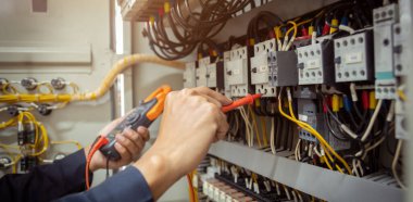 Elektrik mühendisi, devre kesici ve kablo tesisat sistemindeki elektrik akımını kontrol etmek için ölçüm ekipmanı kullanıyor. .