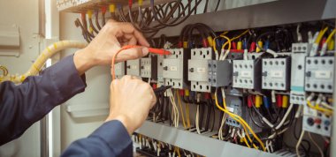 Elektrik mühendisi, devre kesici ve kablo tesisat sistemindeki elektrik akımını kontrol etmek için ölçüm ekipmanı kullanıyor. .