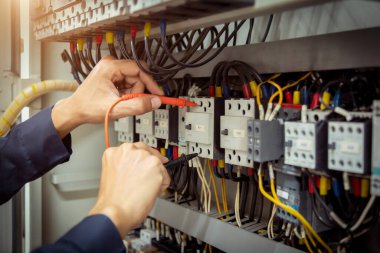 Elektrik mühendisi, devre kesici ve kablo tesisat sistemindeki elektrik akımını kontrol etmek için ölçüm ekipmanı kullanıyor. .