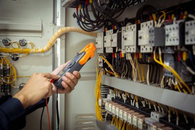Elektrik mühendisi, devre kesici ve kablo tesisat sistemindeki elektrik akımını kontrol etmek için ölçüm ekipmanı kullanıyor. .