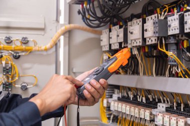 Elektrik mühendisi, devre kesici ve kablo tesisat sistemindeki elektrik akımını kontrol etmek için ölçüm ekipmanı kullanıyor. .