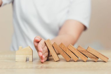 Emlak sigortası. Ve güvenlik konsepti, kadın eli durdurma. Tahta blokların evin üzerine düşmesi riski..