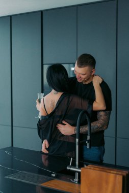 Bir adam ve bir kadın mutfakta sarılıyor. Siyah iç çamaşırlı çift sarılıp şampanya içiyor. Alkollü bir bardak içki, baştan çıkarma ve romantik bir randevu. Aşk