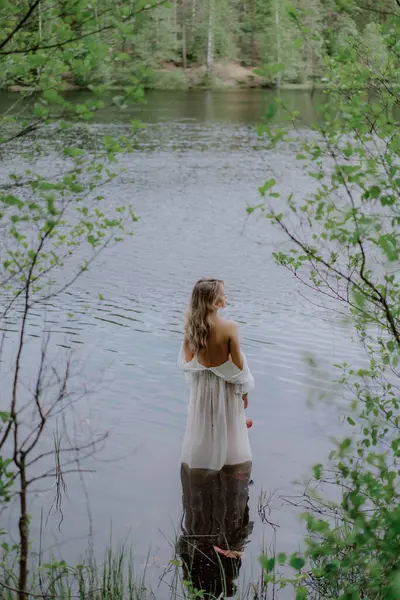 Beyaz şeffaf şeffaf uzun elbisesiyle suda duran kadın. Gölde, gölde ya da denizde yıkanan tanınmayan bir kız. Yaz titreşimleri. Düğün sabahında gelin. Seksi kadın yatak odası..