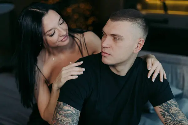 Yatakta oturan bir adam ve kadın. Genç ve güzel bir çift sarılıyor. Kadın erkeği arkadan kucaklıyor. Romantik randevu ya da tatil. Yatak odasındaki ya da otel odasındaki insanlar. Dövme.