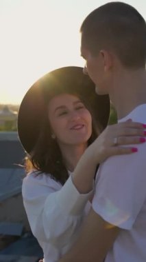 Bir adam ve bir kadın çatıda yürüyor, sarılıyor ve öpüşüyorlar. Saint-Petersburg, Rusya 'da çatı. Gün batımında şehirde romantik bir çift buluşması. Dikey