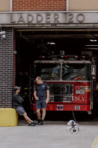 NEW YORK, ABD - 15 Nisan 2024: İtfaiyeciler New York 'taki Ladder 20' nin dışında dinleniyor, bu güzel güneşli günde köpekleriyle vakit geçiriyorlar.