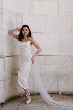 Şık bir gelinlik giyen çarpıcı bir gelin çok zarif bir şekilde mimari alanda poz veriyor.