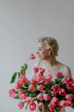 Zarif bir kadın zarif ve canlı pembe lalelerle poz verir yumuşak, rüya gibi bir arkaplana karşı. Mavi iç çamaşırlı bir kadın..