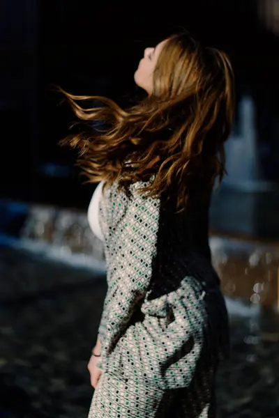 Zarif giyinmiş şık bir girişimci modern bir ofis binasının yanında kendine güveni, kararlılığı ve hareketli bir şehirde güneş altında tarz sahibi bir kadın yürür.