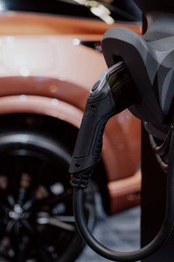 Arka planda modern elektrikli araç teknolojisi sergilenen bir EV şarj istasyonunun yakın çekimi..