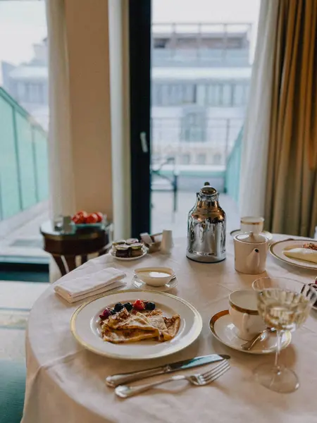 Üzerinde taze böğürtlen bulunan, kahve ve meyve suyu ile servis edilen lüks bir otelde kahvaltı. Şehrin ufuk çizgisine bakan şık bir masanın üzerindeki bu zarif düzenin tadını çıkarın.
