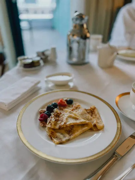 Üzerinde taze böğürtlen bulunan, kahve ve meyve suyu ile servis edilen lüks bir otelde kahvaltı. Şehrin ufuk çizgisine bakan şık bir masanın üzerindeki bu zarif düzenin tadını çıkarın.