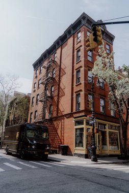 NEW YORK, ABD - 15 Nisan 2024: New York 'ta güzel, büyüleyici bir kahverengi bina, sakin, sessiz bir sokakta teslimat kamyonu sergiliyor.