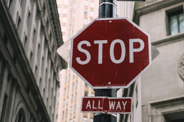 A prominent stop sign with an all-way indication in a bustling city backdrop, emphasizing road safety. clipart