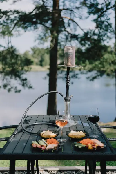Nargile ile rahatlatıcı bir gün. Yemek ve içecekler masada. Açık havada, göl ve orman manzaralı bir yerde yemek yiyeceğiz. Tatilde rahatla..