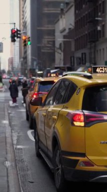 NEW YORK, ABD - 17 Şubat 2024: Gökdelenlerden ve parlak trafik ışıklarından geçen hareketli bir şehir caddesi sarı taksilerle doludur