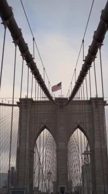 Brooklyn Köprüsü 'nün nefes kesici manzarası ikonik kemerlerini New York' ta dalgalanan Amerikan bayrağının yanında sergiliyor.