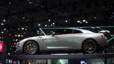 NEW YORK, ABD - 30 Mart 2024: Lüks ve yüksek performansı temsil eden prestijli bir otomobil fuarında parlak bir gümüş spor araba sergileniyor. Nissan GTR