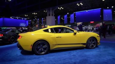 NEW YORK, ABD - 30 Mart 2024: Modern tasarım ve olağanüstü performansı ön plana çıkaran çarpıcı sarı bir spor araba bir otomobil fuarında sergileniyor