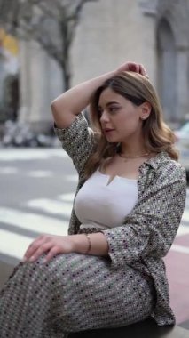 Modayı takip eden genç bir kadın, şehir caddesinde rahat ve zarif bir atmosfer yaratarak, modern ve modaya uygun bir yaşam tarzını somutlaştırarak, günlük kıyafetleri içinde kendine güven ve tarz yayar.