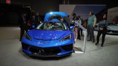 NEW YORK, ABD - 30 Mart 2024 Büyüleyici mavi bir Corvette, büyüleyici katılımcılarla çevrili heyecan verici bir otomobil fuarında güzel bir şekilde sergilendi