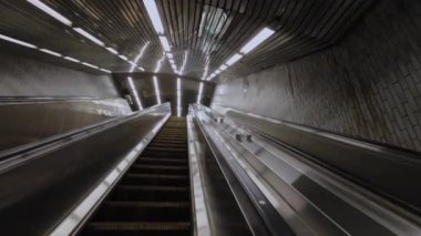 Bir metro istasyonunda parlak ve canlı ışıklarla aydınlatılmış geleceksel bir yürüyen merdiven.