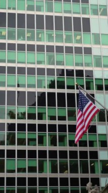 Güzel tasarlanmış yeşil cam pencerelerden yansıyan bayrak. Gösterişli modern cam binalarda Amerikan Bayrağı