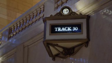 Güzel aydınlatılmış bir pist tabelası, klasik mimarisini sergileyen büyük bir tren istasyonunda görülebilir.