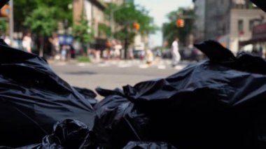 Şehir yaşamının hareketli aktiviteleri arasında kamyondan toplanan siyah çöp torbalarını yakalayan bir manzara. New York sokağı.