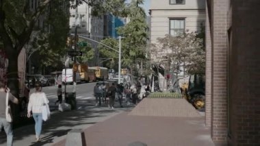 NEW YORK, ABD - 31 Ekim 2024: Sayısız yayaya, yemyeşil ağaçlara ve metropol bölgesinde yoğun trafik yoğunluğuna sahip canlı bir şehir sokağı