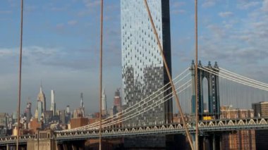 İkonik Brooklyn Köprüsü, canlı bir gökdelene karşı gururla yükselen çağdaş gökdelenleri ustalıkla çerçeveler. New York 'taki Manhattan Köprüsü.