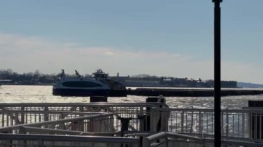 Resimli bir liman sahnesinde New York 'ta güneşli bir günde zarif bir şekilde süzülen bir feribot görülüyor.