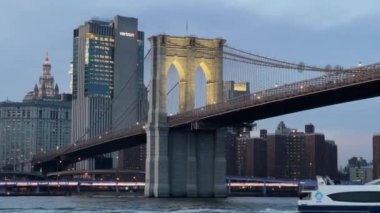 NEW YORK, ABD - 2 Şubat 2024 Brooklyn Köprüsü 'nün alacakaranlıkta parlak bir şekilde aydınlatılmış, canlı şehrin ufuk çizgisine karşı kurulmuş görüntüsü