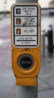 Bu resim, New York 'ta bir yaya geçidinin yakınında bulunan parlak sarı bir trafik sinyal düğmesinin ayrıntılı bir yakın çekimini gösteriyor