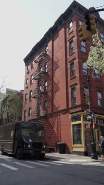 NEW YORK, ABD - 30 Mart 2024: Parlak güneşli gökyüzünün altında bir dağıtım aracının yanında tarihi bir tuğla bina sergilenen şehir manzarası