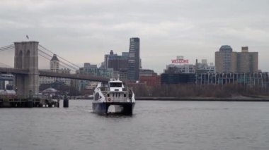 Brooklyn Köprüsü ve Manhattan silueti arka planda görünen bir feribot, Doğu Nehri boyunca süzülür.