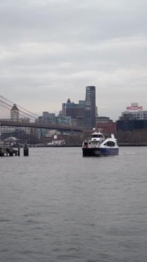 Brooklyn Köprüsü ve Manhattan silueti arka planda görünen bir feribot, Doğu Nehri boyunca süzülür.
