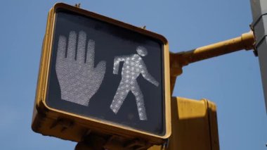 Açık bir şekilde görülebilen, parlak mavi gökyüzü arka planına karşı yayaya ait bir trafik sinyali. Lütfen dur ve yaya trafik ışığı gösterdiğinde yürümeye devam et.