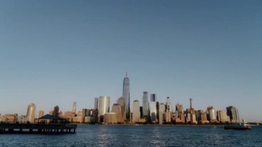 Nefes kesen modern şehir siluetinin güzel bir günde deniz kıyısındaki görkemli manzarasını deneyimleyin. New York 'taki Manhattan şehir merkezi finans bölgesi. Gün batımı zaman aşımı.