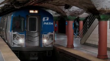 NEW YORK, ABD - 6 Kasım 2024: Enerji dolu hareketli bir metro istasyonu, gelen bir treni, şehir mimarisini ve kalabalık banliyöleri gösteriyor