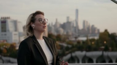 Terzi kıyafeti giymiş kararlı bir kadın canlı bir şehir manzarasını, özgüveni ve şehir hayatını gözden kaçırıyor. New York 'ta kablosuz kulaklıkla konuşan kişi..